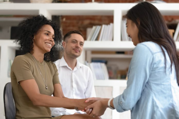 A woman shaking her colleague's hand and showing empathy in the workplace.