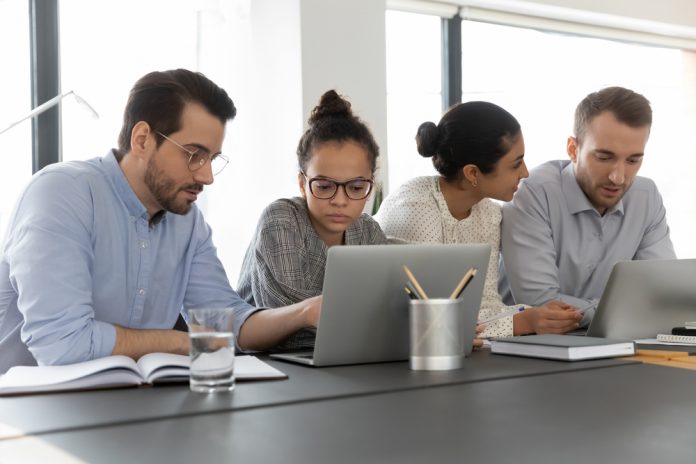 two women and two men colleagues learning together on a lap top.