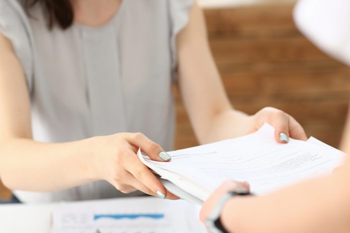 female potential employee passing stack of papers to a potential employer