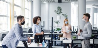 Teams returning to the office with masks on.