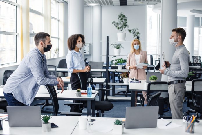 Teams returning to the office with masks on.