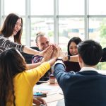 group of colleagues high fiving one another.