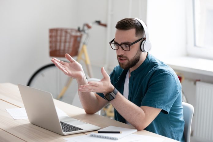 Focused,Young,Businessman,In,Eyewear,Wearing,Headphones,,Holding,Video,Call