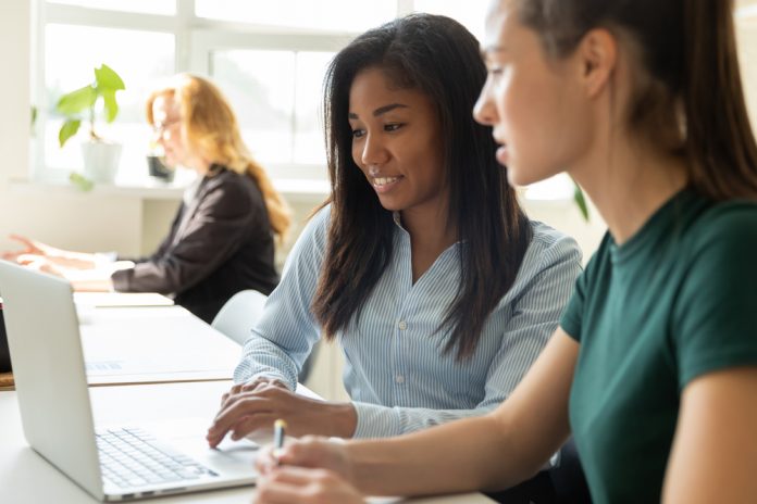 Smiling,Millennial,Multiracial,Female,Employees,Cooperate,Working,Together,On,Laptop