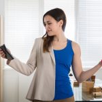 Young,Businesswoman,Holding,Calculator,Exercising,With,Dumbbells,In,Office