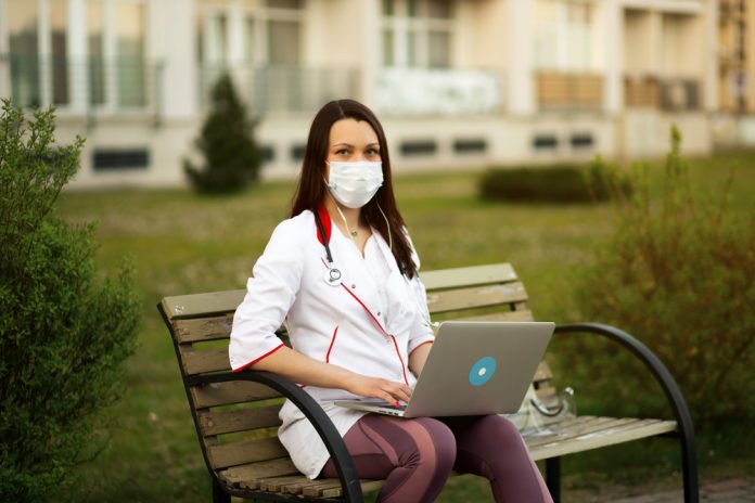 Female,Medical,Doctor,In,Mask,And,Stethoscope,Uses,Laptop,And