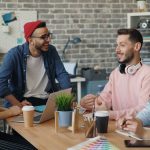 two girls and two guys sitting together at a table, collaborating.