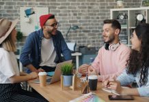 two girls and two guys sitting together at a table, collaborating.