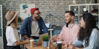 two girls and two guys sitting together at a table, collaborating.