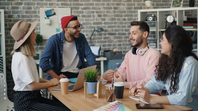 Belonging: How Employees Can Feel It In Their Personal And Professional Lives two girls and two guys sitting together at a table, collaborating.
