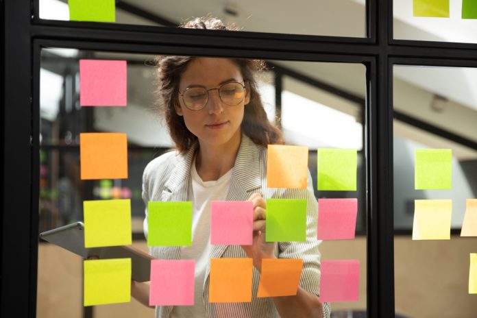 Confident,Focused,Businesswoman,Wearing,Glasses,Writing,Ideas,Or,Tasks,On