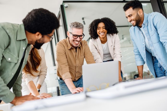 A,Cheerful,Group,Of,Diverse,Coworkers,Lean,In,Around,A