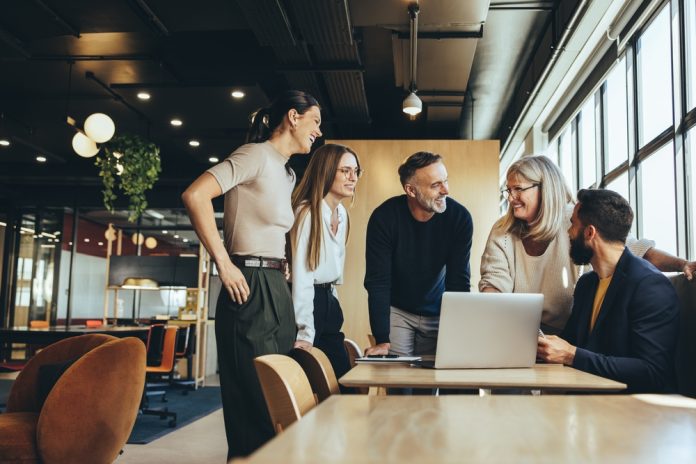 Smiling,Businesspeople,Having,A,Discussion,While,Collaborating,On,A,New