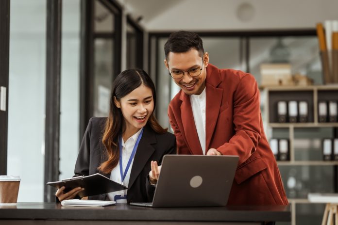 Middle-aged,Businessman,And,Young,Asian,Businesswoman,Diligently,Working,At,Desks,