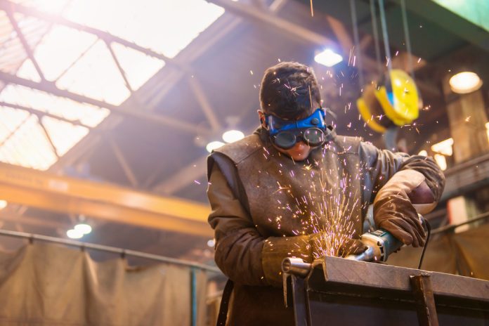 Young,Man,With,Protective,Goggles,Welding,In,A,Factory
