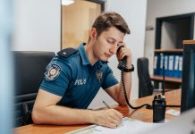 a police officer sitting at his desk in uniform, answering a call.