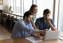 three people sitting around a computer.