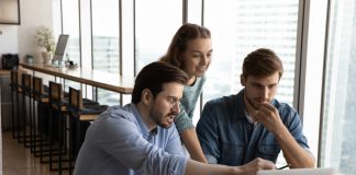 three people sitting around a computer.