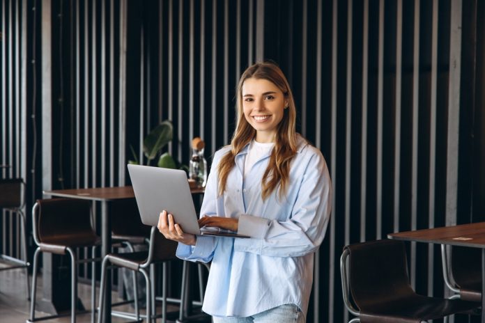 Young,Businesswoman,Smiling,And,Using,Laptop,,Enjoying,Remote,Work,In
