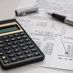 a picture of a desk with a calculator and a sheet and pen.