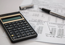 a picture of a desk with a calculator and a sheet and pen.