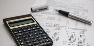 a picture of a desk with a calculator and a sheet and pen.