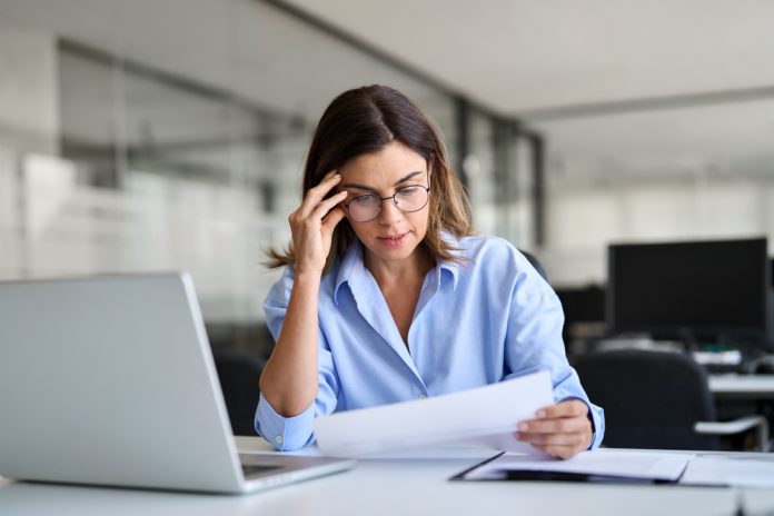 Worried,Mature,Professional,Business,Woman,Reading,Bad,News,In,Document