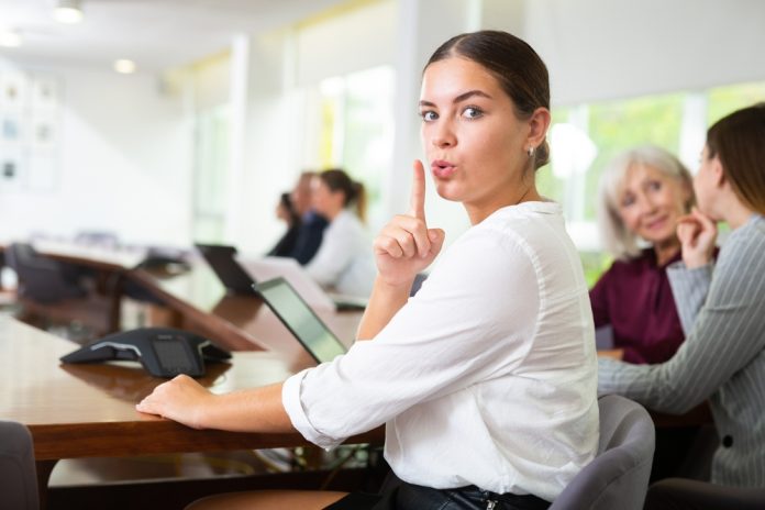 Young,Woman,Manager,Sitting,At,Desk,,Making,Silence,Gesture,With