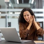 Beyond the Ringing: Why Tinnitus in the Workplace Is More Than a Minor Distraction A woman at work dealing with ringing in her ear.