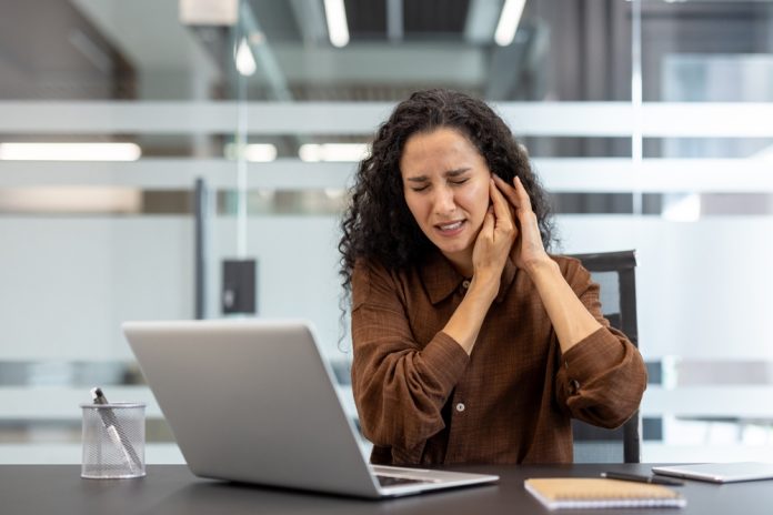 A woman at work dealing with ringing in her ear.