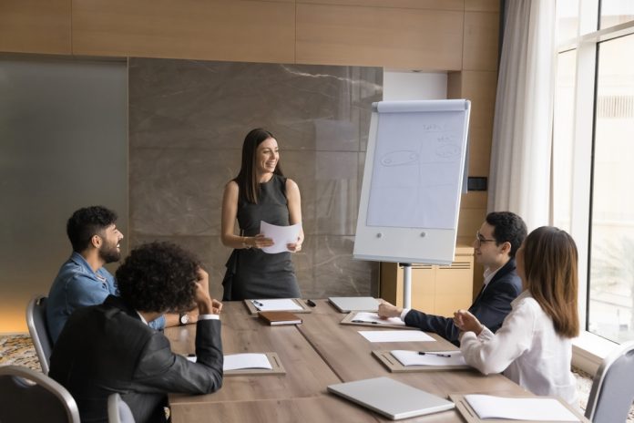 Behind the Training Theater Curtain on the job training - a woman presenting in front of her colleagues.