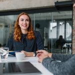 a red headed woman having coffee with a colleague
