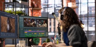 a woman sitting at a desk with two monitors, editing a video