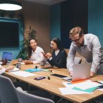 Diverse,Business,Team,Discussing,Project,Strategy,Young,Man,Leaning,Over