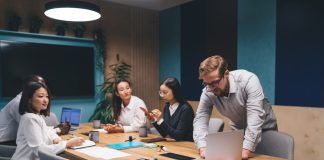 Diverse,Business,Team,Discussing,Project,Strategy,Young,Man,Leaning,Over