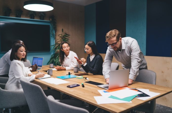 Diverse,Business,Team,Discussing,Project,Strategy,Young,Man,Leaning,Over
