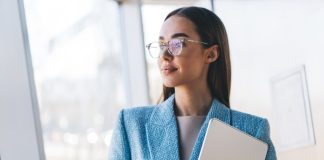 Confident,Freelancer,Holding,Tablet,Near,Window,,Gazing,Thoughtfully,Outside,,Symbolizing