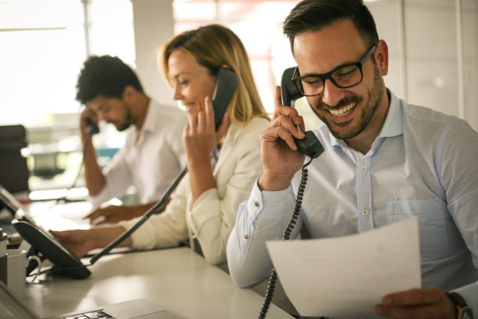 group of people working in an office handling phone calls