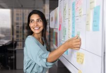Smiling,Latina,Professional,Woman,Placing,Sticky,Notes,On,Large,Planning