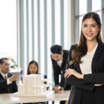 Confident,Businesswoman,With,Crossed,Arms,Smiling,In,The,Foreground,,With